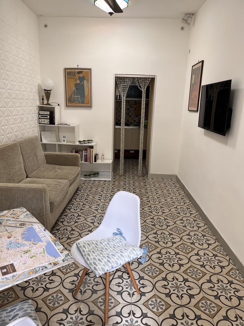 The living room, with a sofa, a table with a map of Naples and the patterned tile floor that runs through the whole apartment.