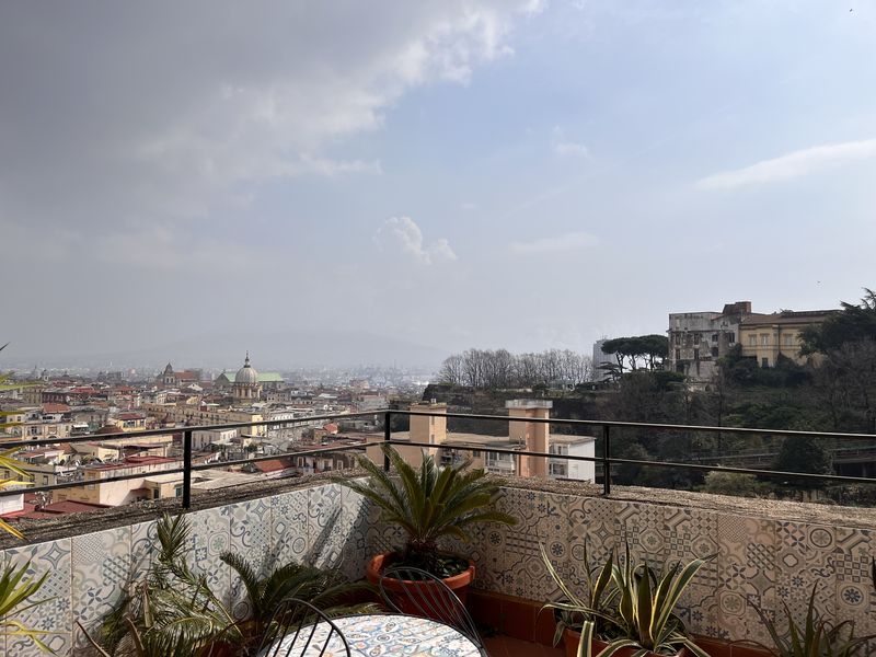 Across the rooftops and domes of Naples, with Vesuvius in the haze on the horizon.