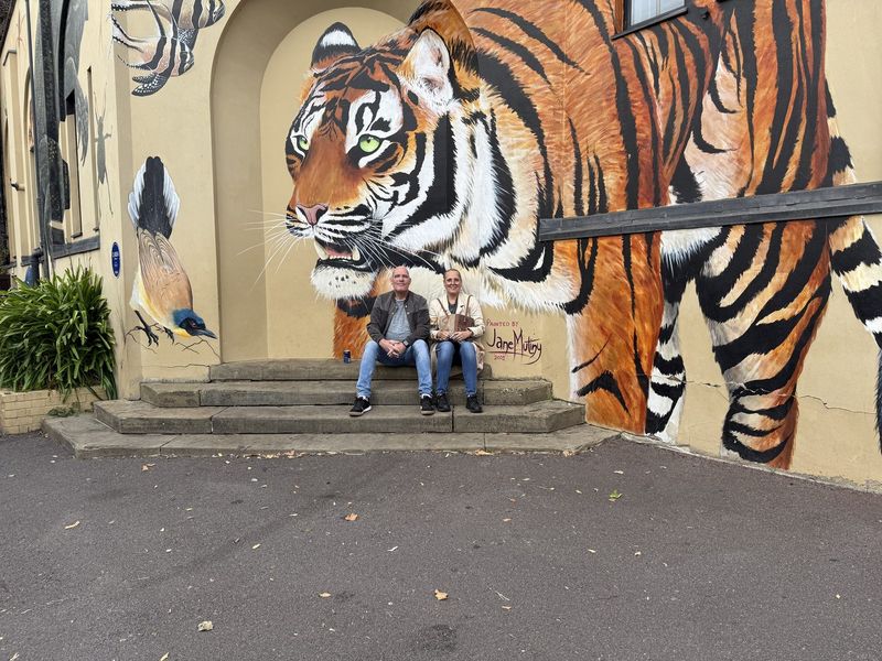 Marc e Liek sui gradini accanto al grande murale della tigre.