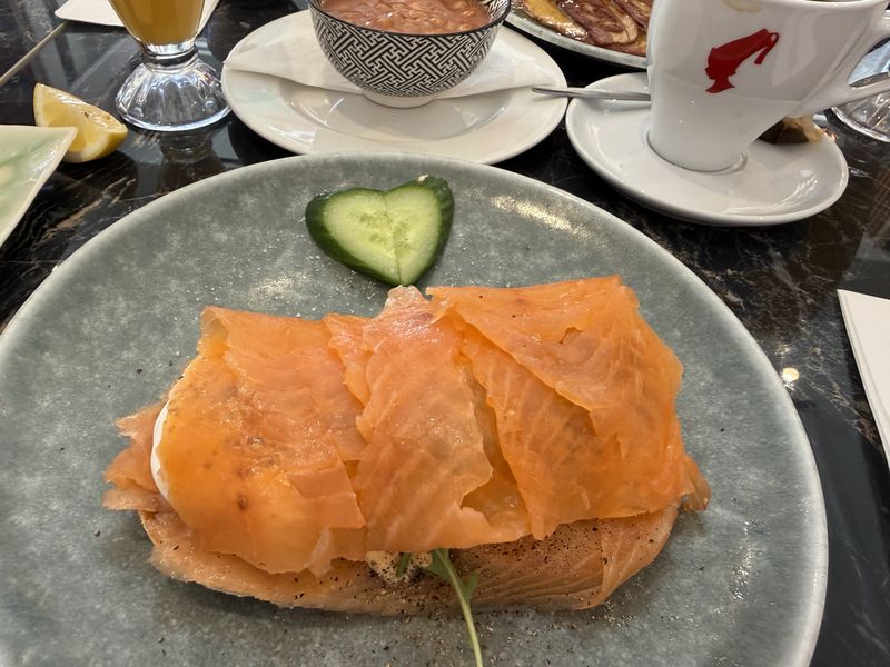 Uovo in camicia con tanto salmone in più e salsa olandese, accompagnato da una fettina di cetriolo a forma di cuore.