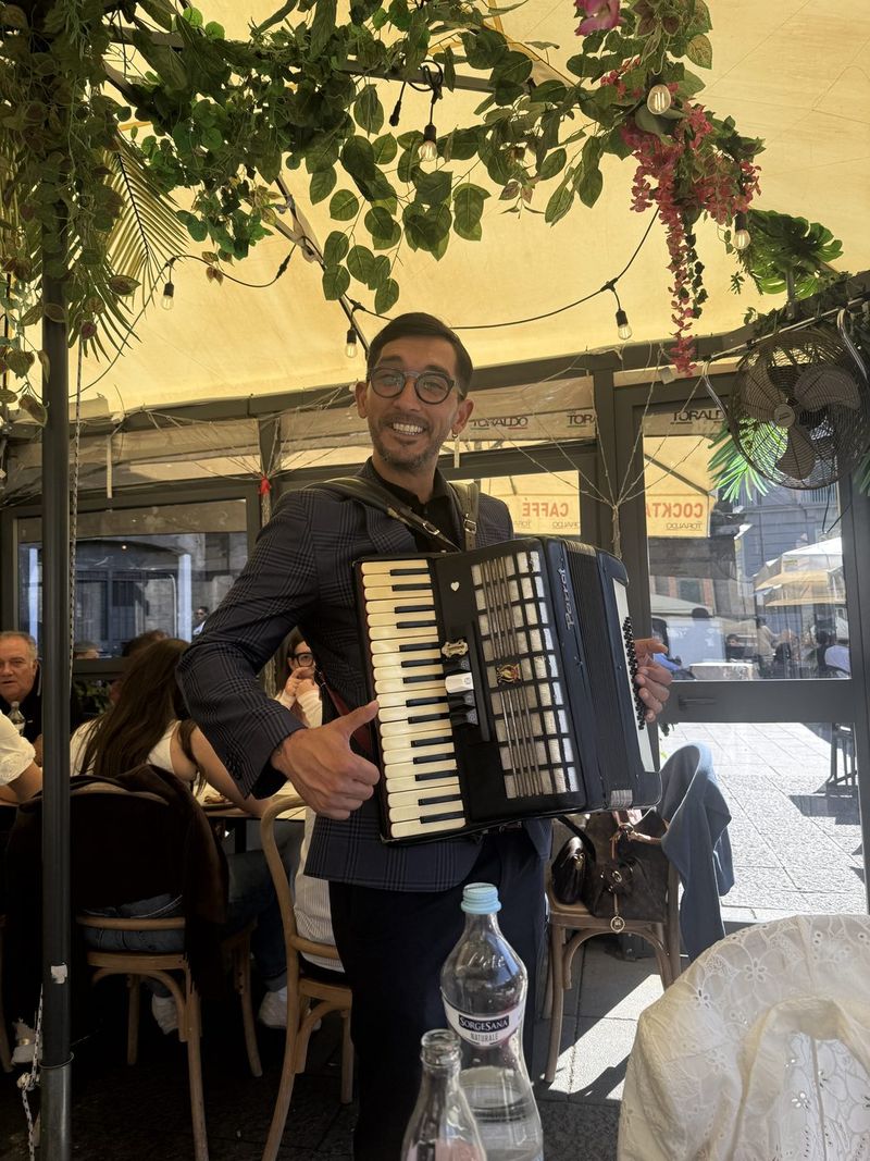 An accordion player comes past the tables.